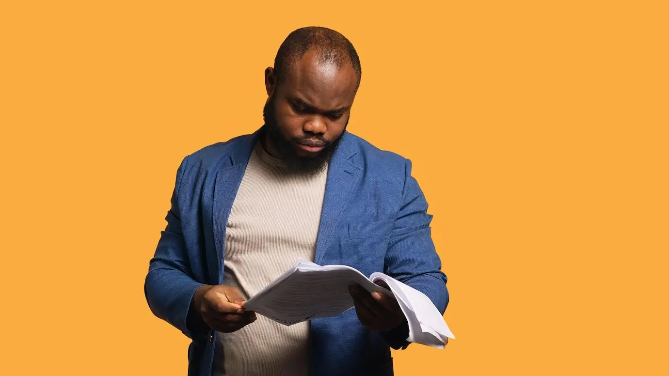 Homme parcourant des dossiers de rapports, les jetant avec colère, se sentant surmené.